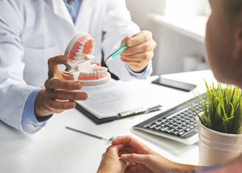 a dentist showing a patient a model of teeth