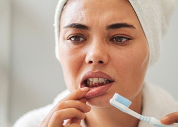 A woman looking at her gums in the mirror