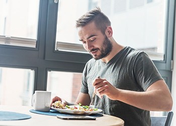 Man at table next to window eating a healthy meal