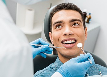 Man smiling at dentist approaching to examine his teeth