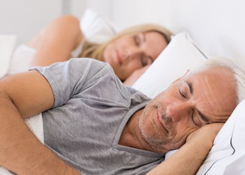 Older man and woman sleeping in bed