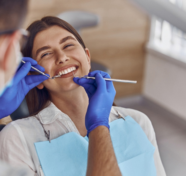A smiling woman preparing to receive a dental checkup