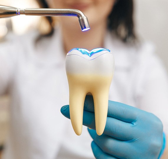 Dentist demonstrating tooth-colored repair on large model tooth