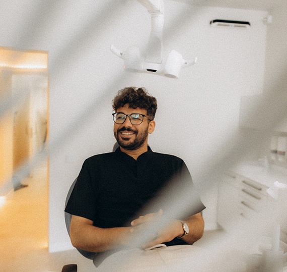 Patient with black glasses smiling in treatment chair