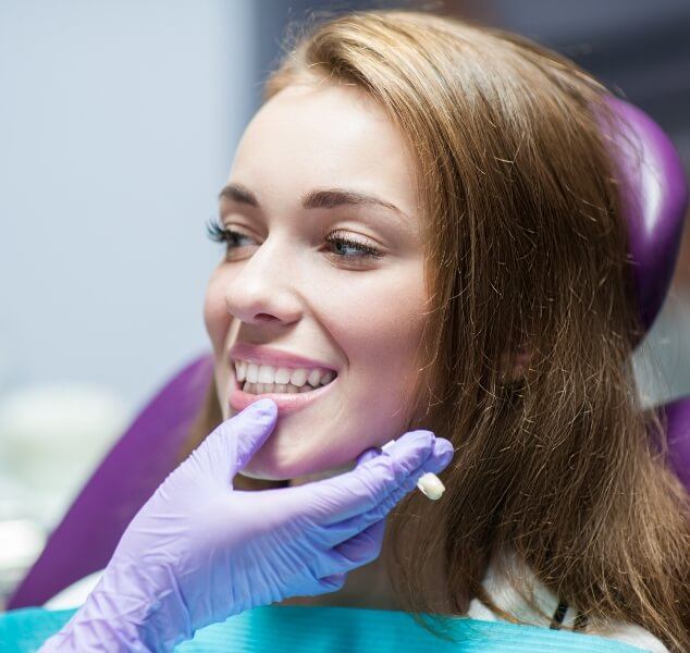 Woman in dental chair as dentist examines her smile