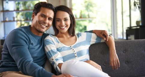 Man and woman smiling on couch after dental services in Springfield
