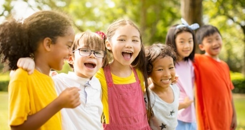 Group of kids standing in line outdoors with their arms around each others shoulders