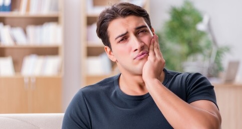 Young man holding his cheek in pain