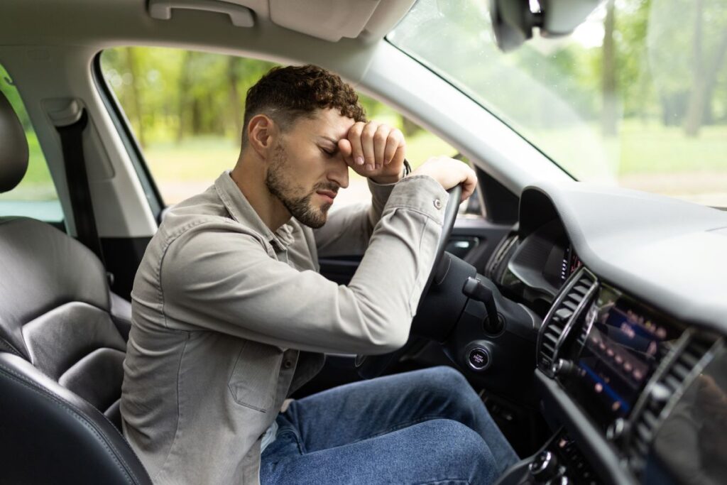 A tired man driving a car