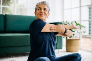 Healthy senior woman sitting on the floor and stretching